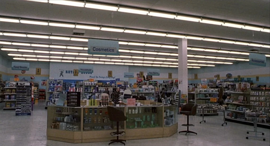 The Good Girl (2002) movie still: wide — A quiet retail store interior features long aisles of merchandise and shelving displays. Glass display…