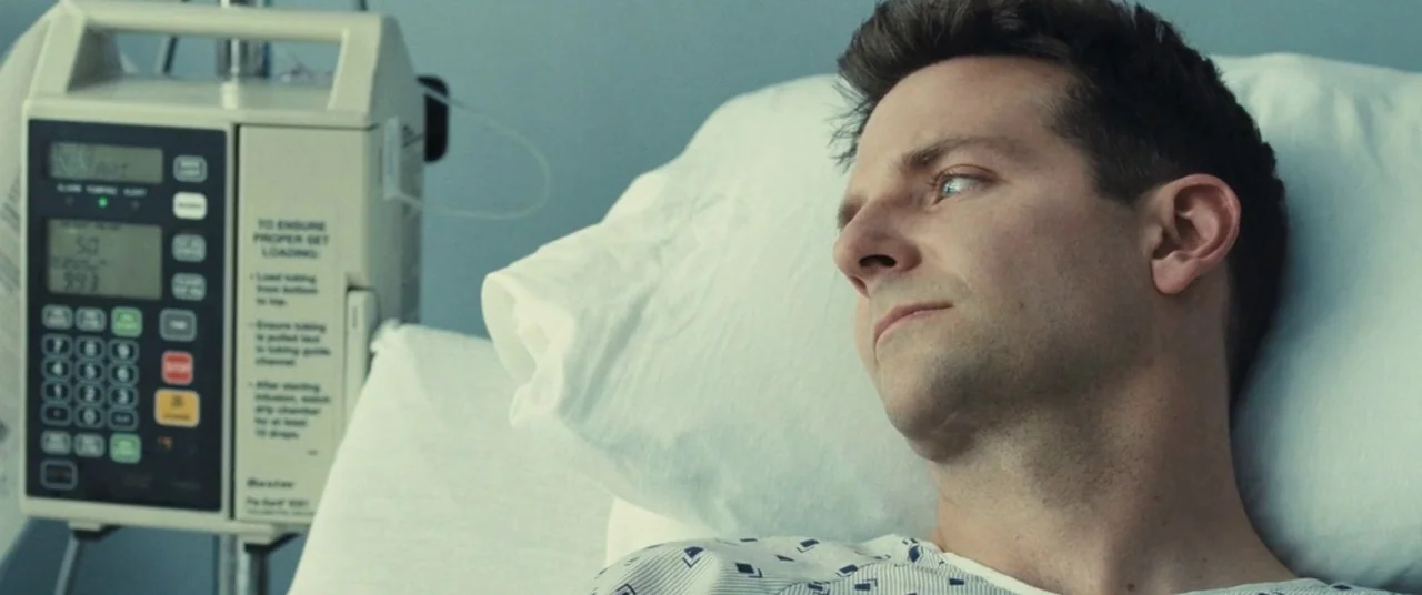 The Place Beyond The Pines (2012) movie still: closeup — A man lies in a hospital bed with a digital IV pump nearby. The setting is a sterile…