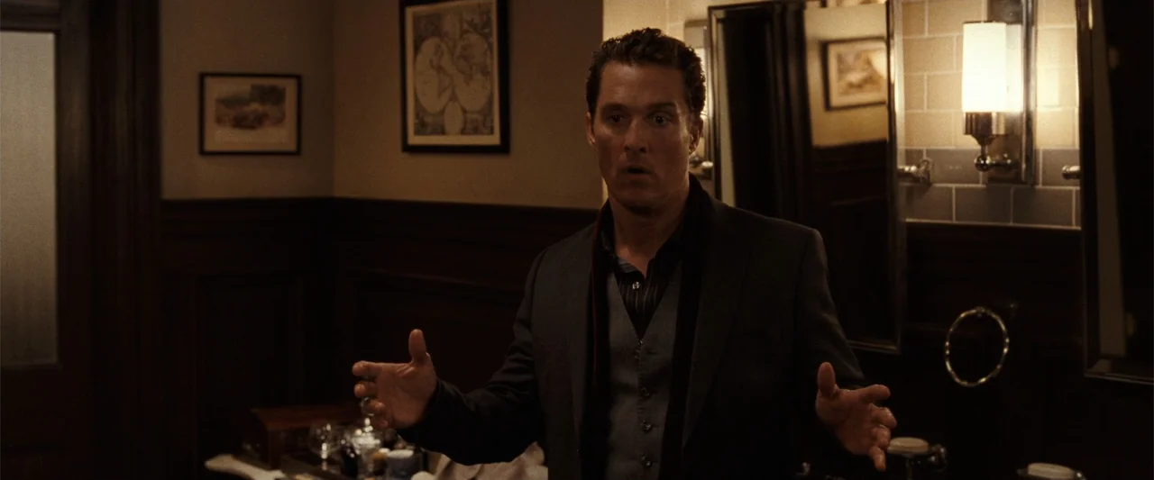 Ghosts of Girlfriends Past (2009) movie still: medium — A dimly lit room with wood-paneled walls and a wall-mounted light fixture above a mirror. A…