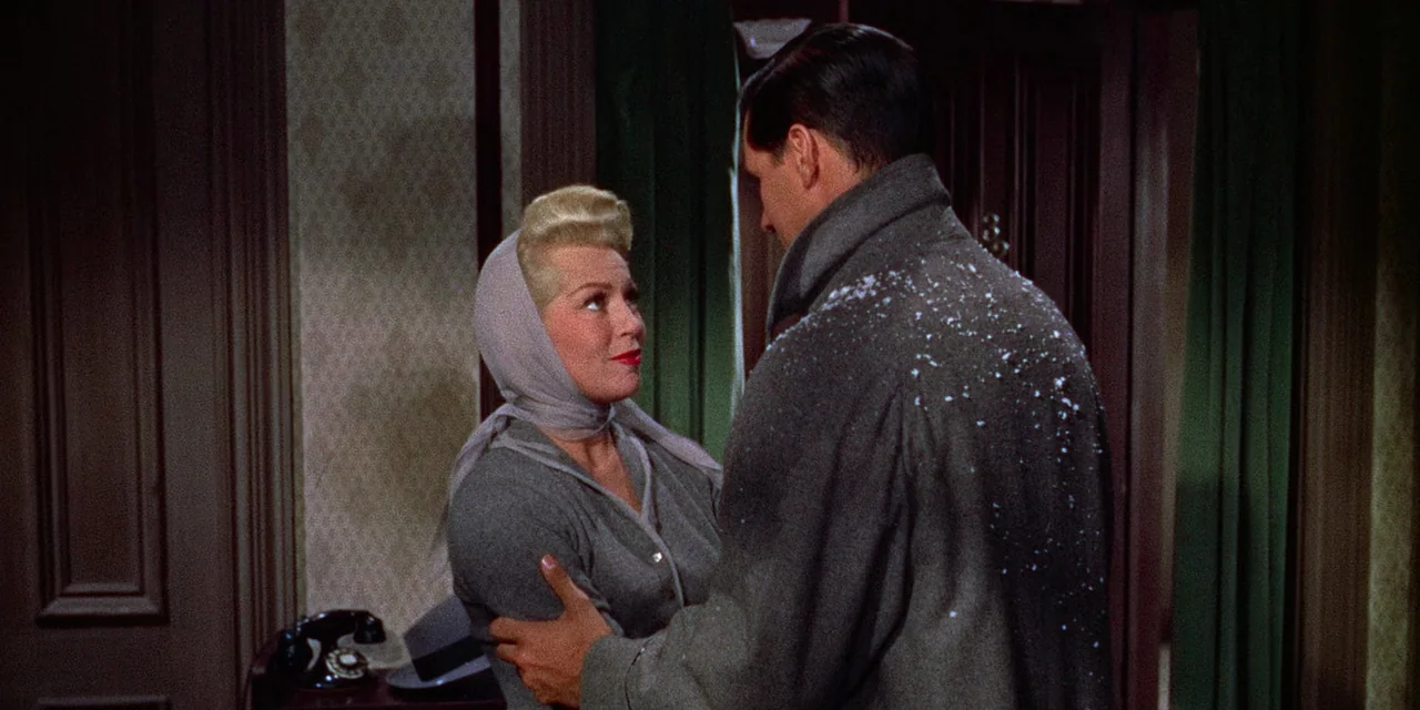 Imitation of Life (1959) movie still: medium — A dimly lit indoor threshold featuring green curtains and patterned wallpaper. A man with snowy…