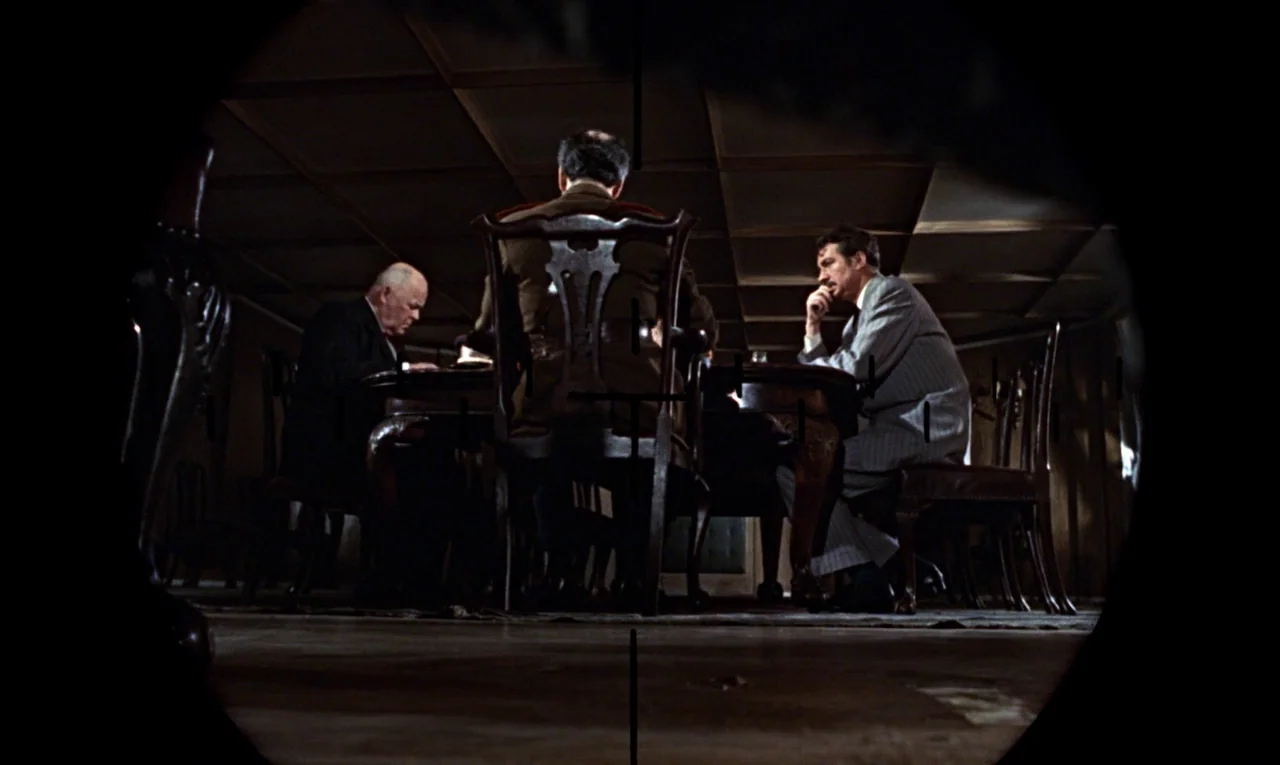 From Russia With Love (1963) movie still: medium — A dimly lit room with wood-paneled walls and a ceiling grid pattern. Three men sit at a large…