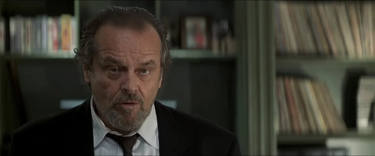 Anger Management (2003) movie still: closeup — An interior space features shelves filled with vinyl records in the background. A man in a dark suit…