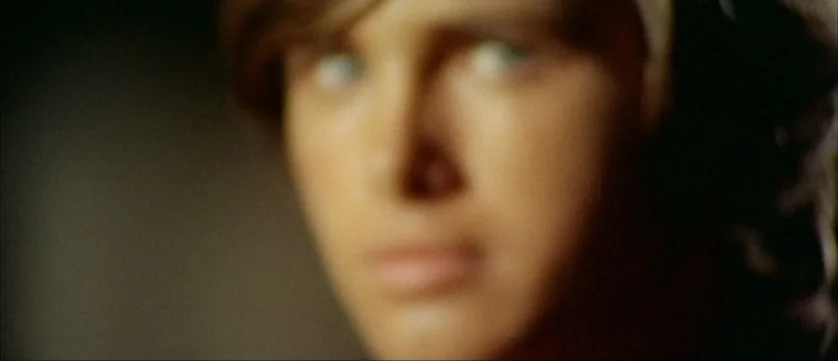 Django Kill (1967) movie still: closeup — An out-of-focus close up shows a man's face against a dark background. The subject gazes forward with…
