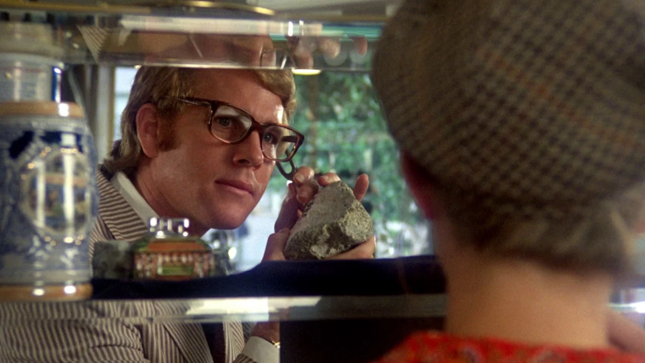 What’s Up, Doc? (1972) movie still: medium — A glass display case containing various small objects separates two people in a room. A man with…