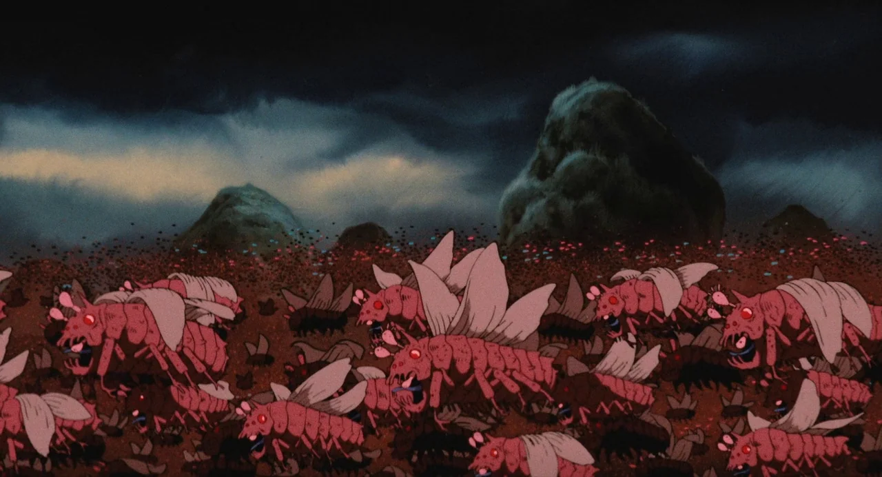 Nausicaä of the Valley of the Wind (1984) movie still: wide — A dark rocky desert landscape lies under a stormy, clouded night sky. A dense swarm of…
