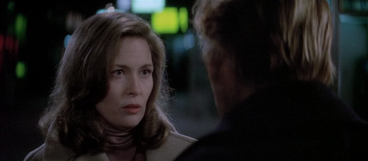 Three Days of the Condor (1975) movie still: closeup — An urban outdoor setting at night with blurry city lights in the dark background. A woman in…
