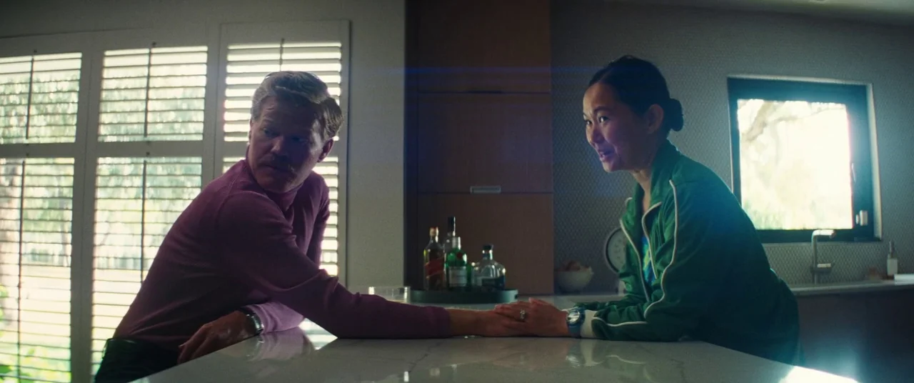 Kinds of Kindness (2024) movie still: medium — A modern kitchen features a marble countertop island with bottles placed on a tray. A man and a woman…