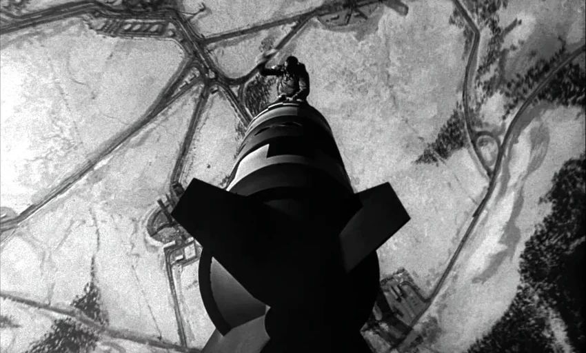 Dr. Strangelove or: How I Learned to Stop Worrying and Love the Bomb (1964) movie still: wide — A man sits astride a large nuclear missile against a…