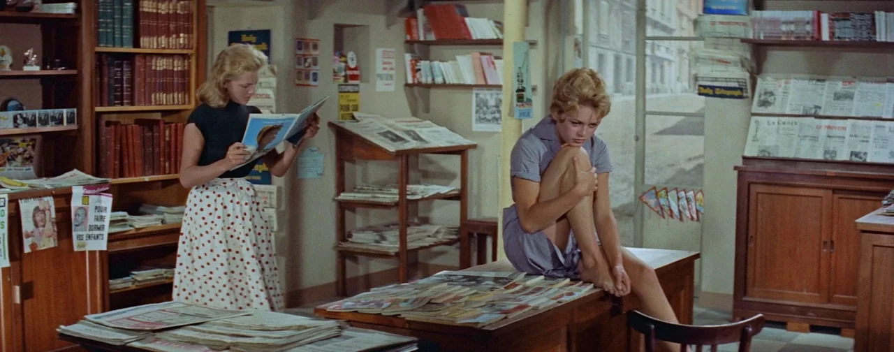 And God Created Woman (1956) movie still: fullbody — A well-stocked shop features wooden shelving units filled with books and various newspapers.…