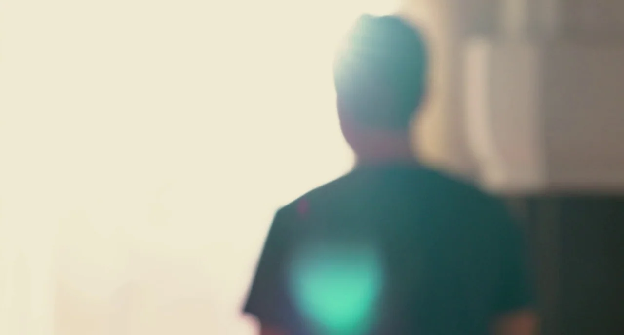 Take This Waltz (2011) movie still: medium — An interior space is illuminated by a bright, overexposed source from a window. A man is positioned…
