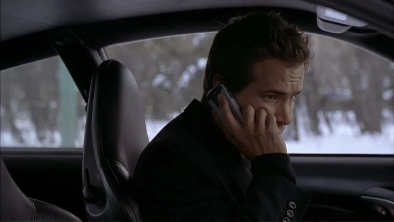 Just Friends (2005) movie still: medium — The interior of a parked car overlooks a blurred snowy environment visible outside. A man wearing a black…