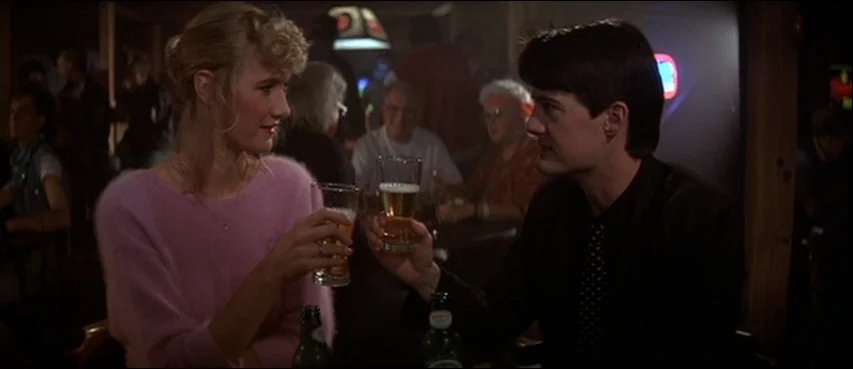 Blue Velvet (1986) movie still: medium — A dimly lit drinking establishment features patrons seated at tables under low illumination. A man and a…