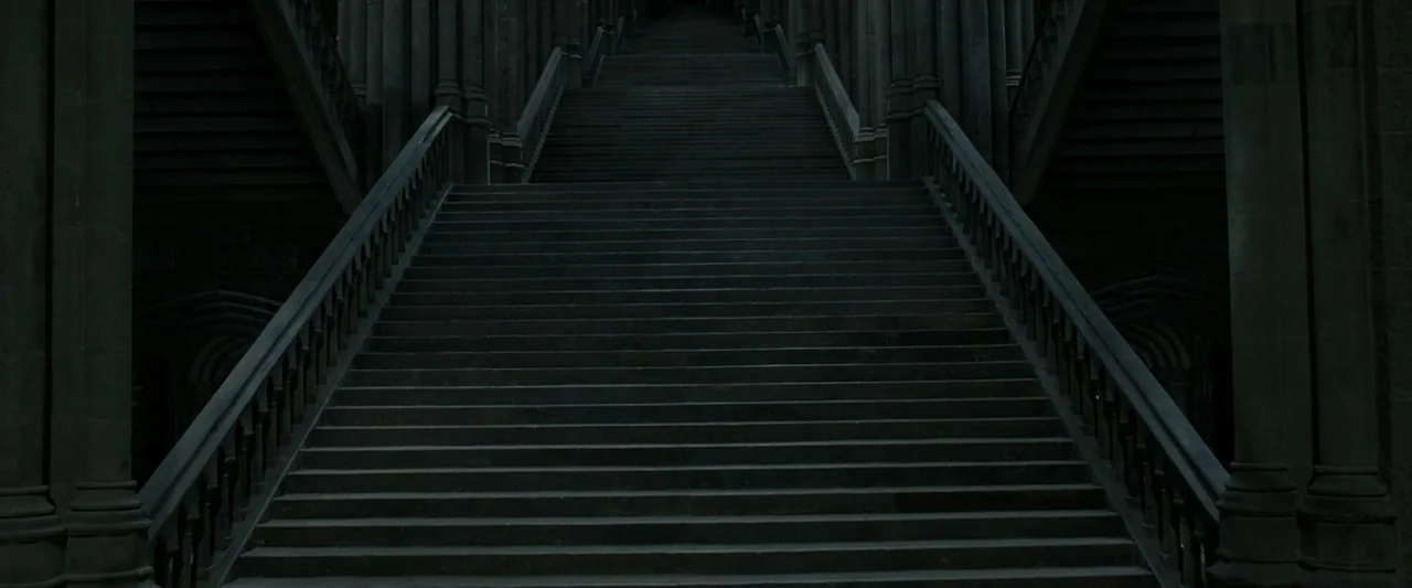 Harry Potter & The Deathly Hallows Part 2 (2011) movie still: establishing — A dark stone staircase ascends symmetrically within a large vaulted…