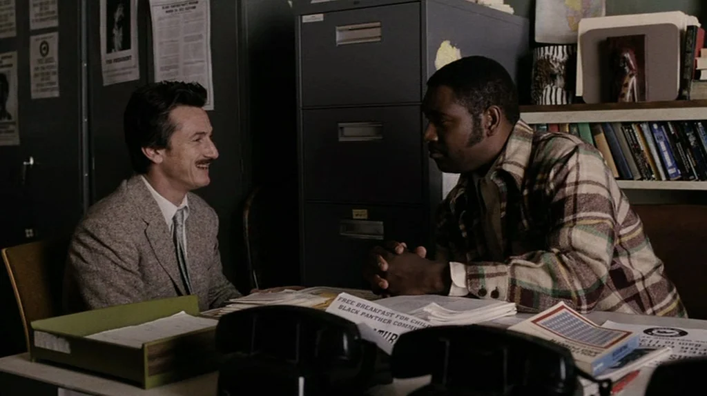 The Assassination of Richard Nixon (2004) movie still: medium — A cluttered 1970s administrative office features tall filing cabinets and stacked…