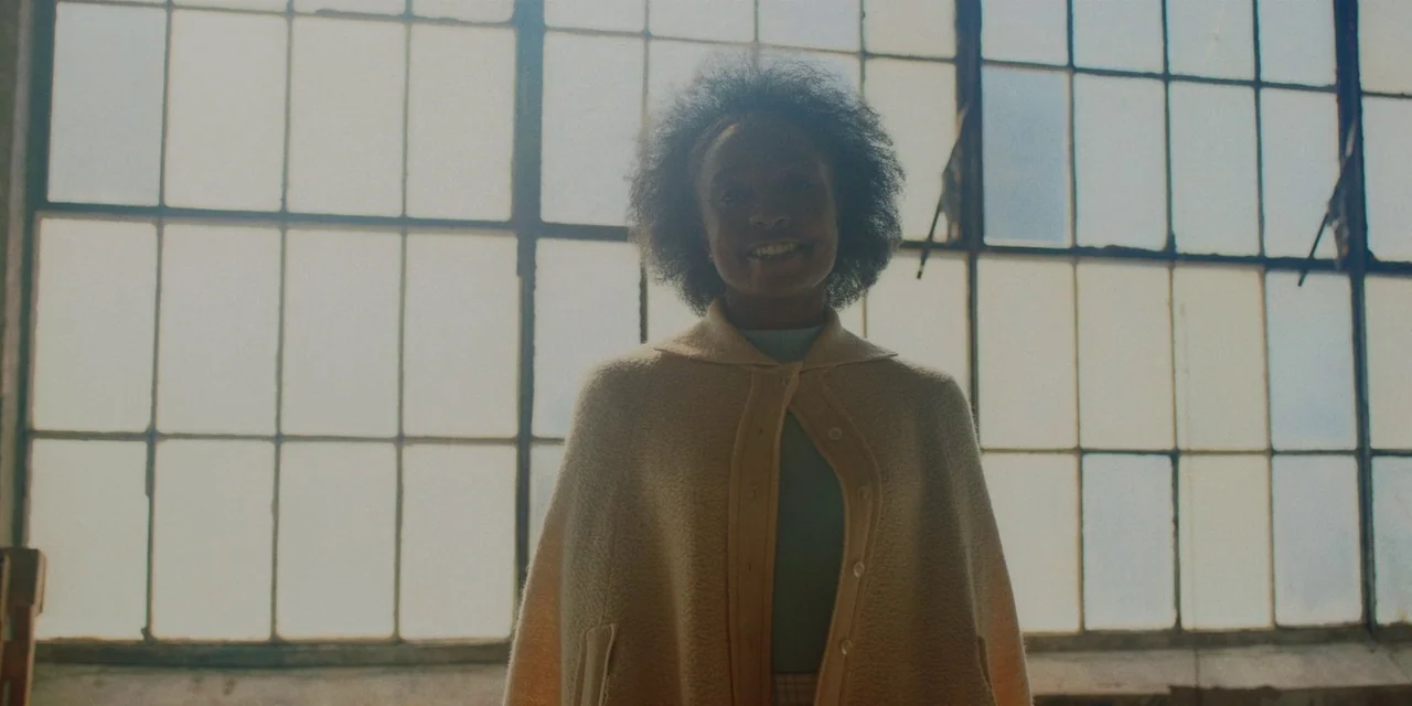 If Beale Street Could Talk (2018) movie still: medium — An interior space with a large window featuring a metal grid frame. A woman stands in front…