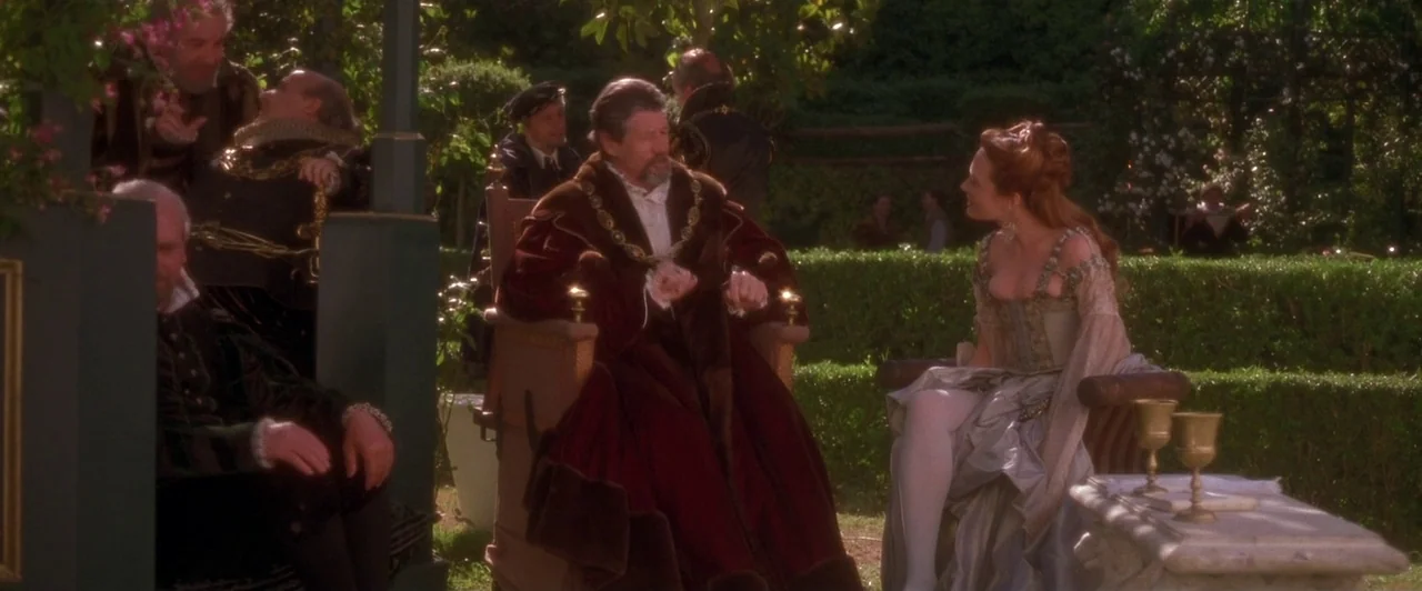 Dangerous Beauty (1998) movie still: fullbody — A manicured courtyard features green hedges, stone furniture, and scattered figures in period…