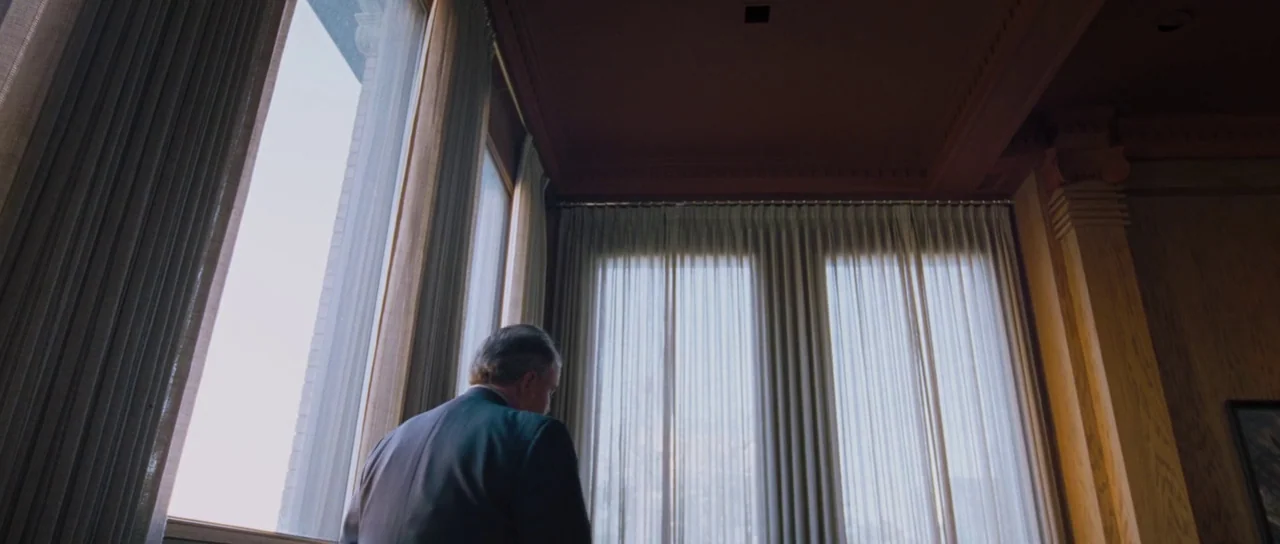 To The Wonder (2012) movie still: medium — A spacious room features high ceilings with dark wood paneling and floor-to-ceiling windows. An older man…