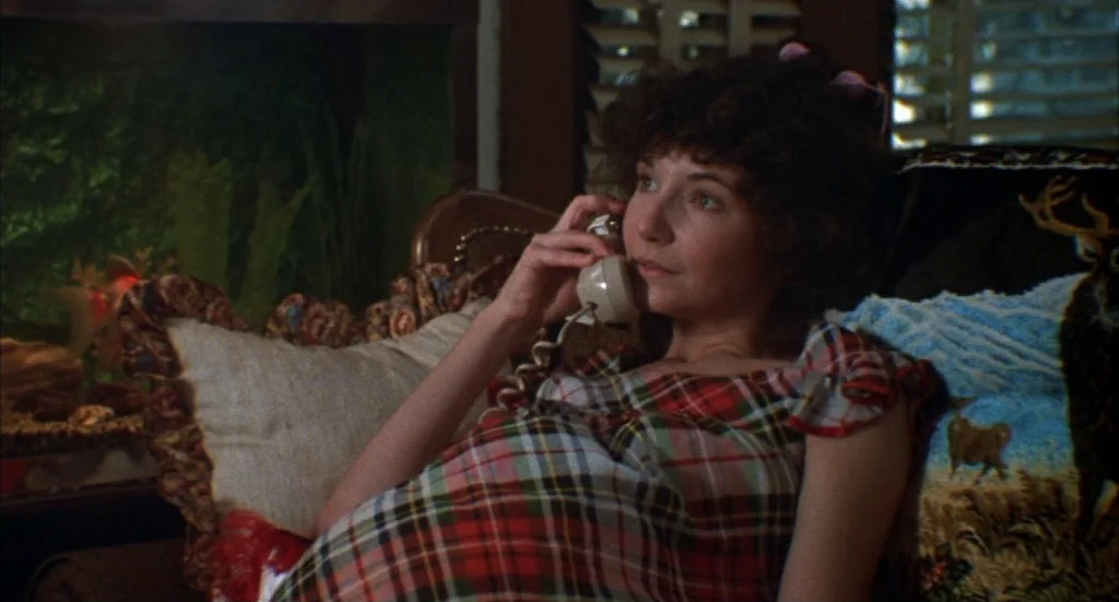 Melvin & Howard (1980) movie still: medium — A woman rests on a sofa beside an aquarium containing green aquatic plants. She holds a vintage corded…