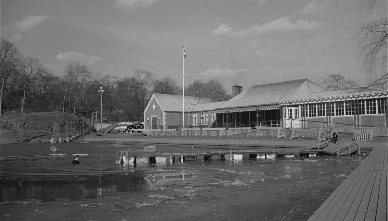 The Manchurian Candidate (1962) movie still: establishing — A stone building sits beside a partially frozen lake with a wooden pier structure. A man…