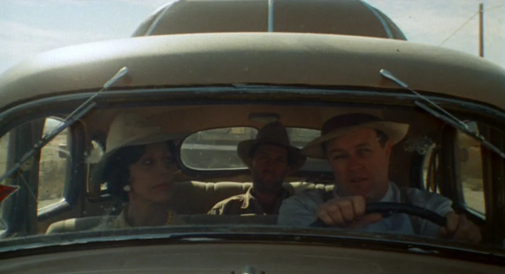Bound For Glory (1976) movie still: medium — Three people sit in the front and back of a vintage car in a rural setting. They are traveling along a…