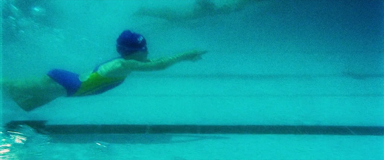 Man on Fire (2004) movie still: wide — An underwater perspective of a wide swimming pool filled with turquoise water. A young child in a swimsuit…