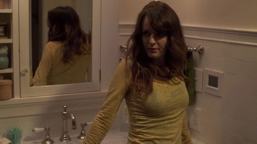 Touchy Feely (2013) movie still: medium — A bright domestic bathroom features white wainscoting and a marble countertop vanity. A woman stands by…