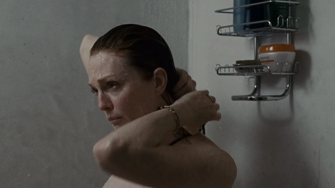 The Kids Are All Right (2010) movie still: closeup — A tiled stall interior with a wire caddy mounted on the wall. A woman with wet hair stands in…