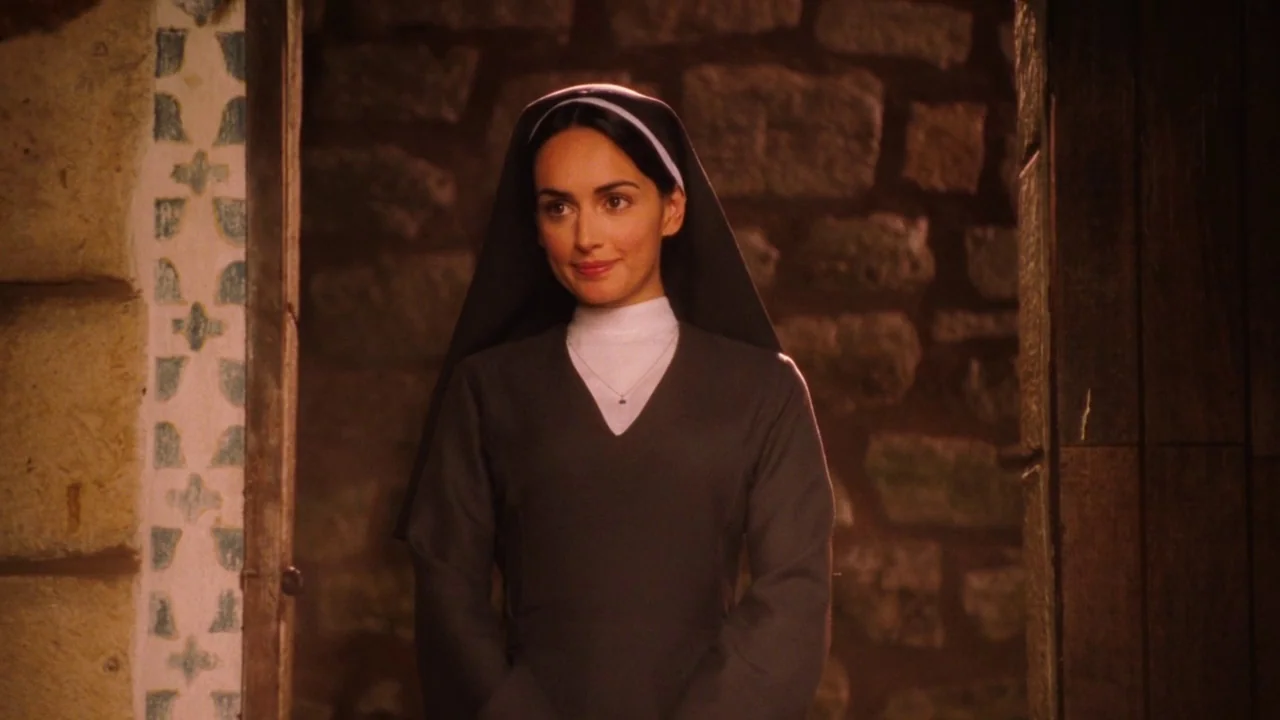 Nacho Libre (2006) movie still: medium — A stone doorway frame surrounds a woman in religious habit. The subject stands centered, looking directly…