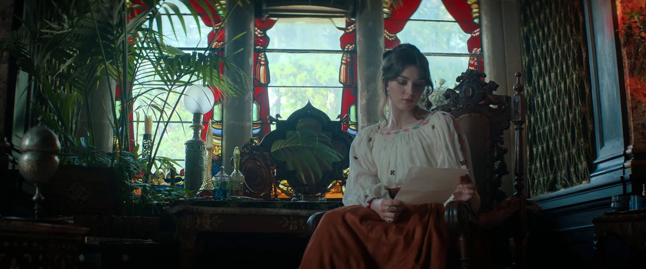 The Count of Monte-Cristo (2024) movie still: medium — A furnished Victorian-era space features stained glass windows with red drapery behind the…