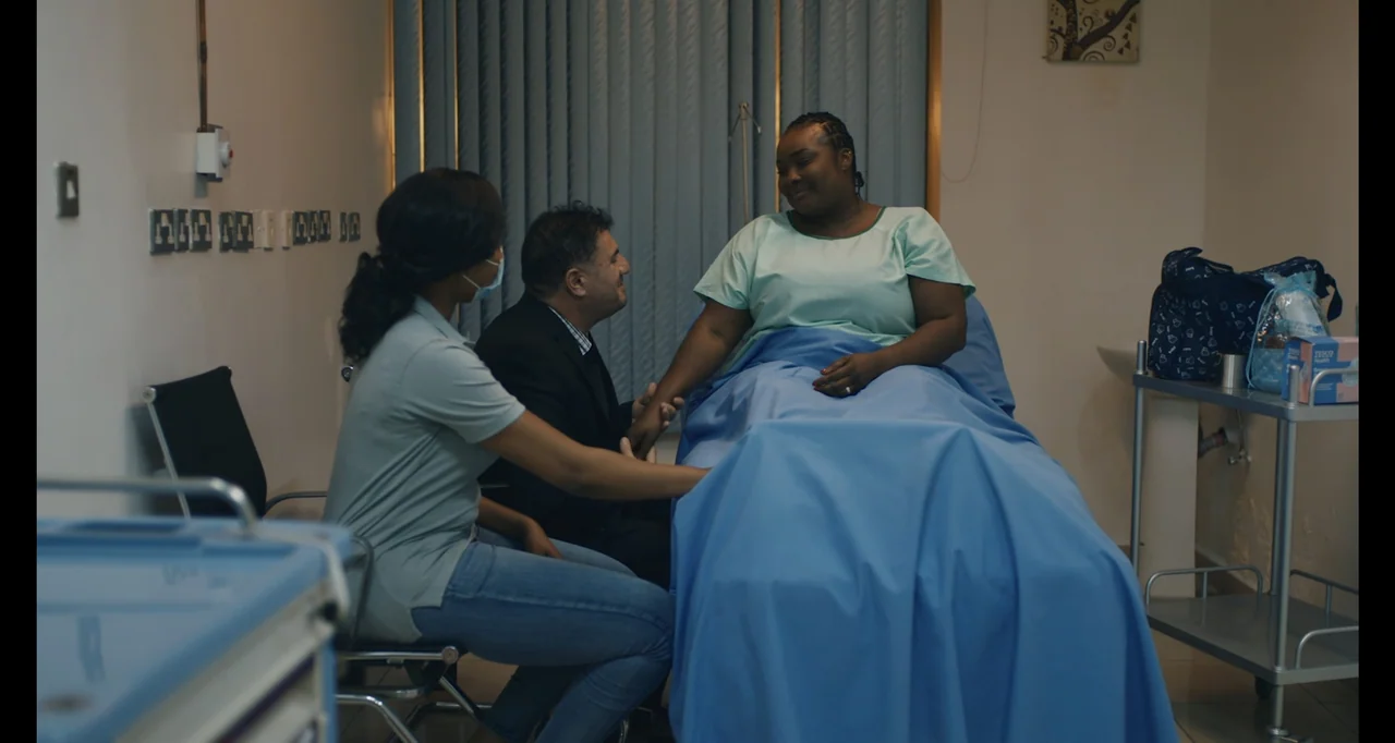 Love In A Pandemic (2023) movie still: medium — A modern hospital room features a patient bed covered in blue linens and medical equipment. Three…