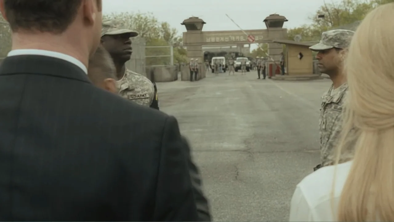 Salt (2010) movie still: medium — A military checkpoint features a paved road leading to a gated entry structure. Soldiers in camouflage uniforms…