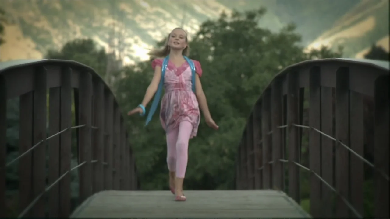 Boathouse Detectives (2010) movie still: fullbody — A wooden pedestrian bridge crosses over greenery with distant mountains in the background. A…