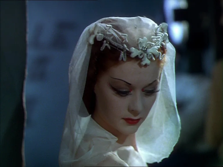 The Red Shoes (1948) movie still: closeup — A close portrait of a woman in a bridal veil inside a stone structure. She keeps her gaze lowered while…