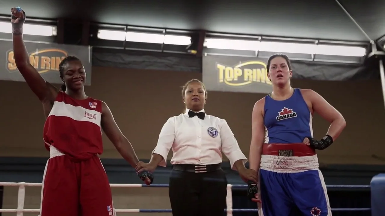 T-Rex (2015) movie still: fullbody — Two female boxers stand in a ring with a referee between them. The referee holds both athletes' hands high as a…