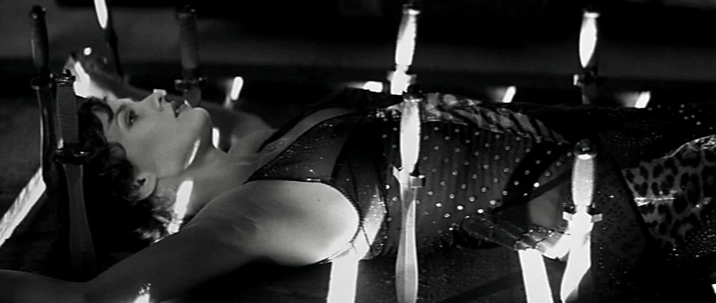 Girl on the Bridge (1999) movie still: A haunting medium closeup captures a woman lying diagonally, her body seemingly impaled or trapped by several…