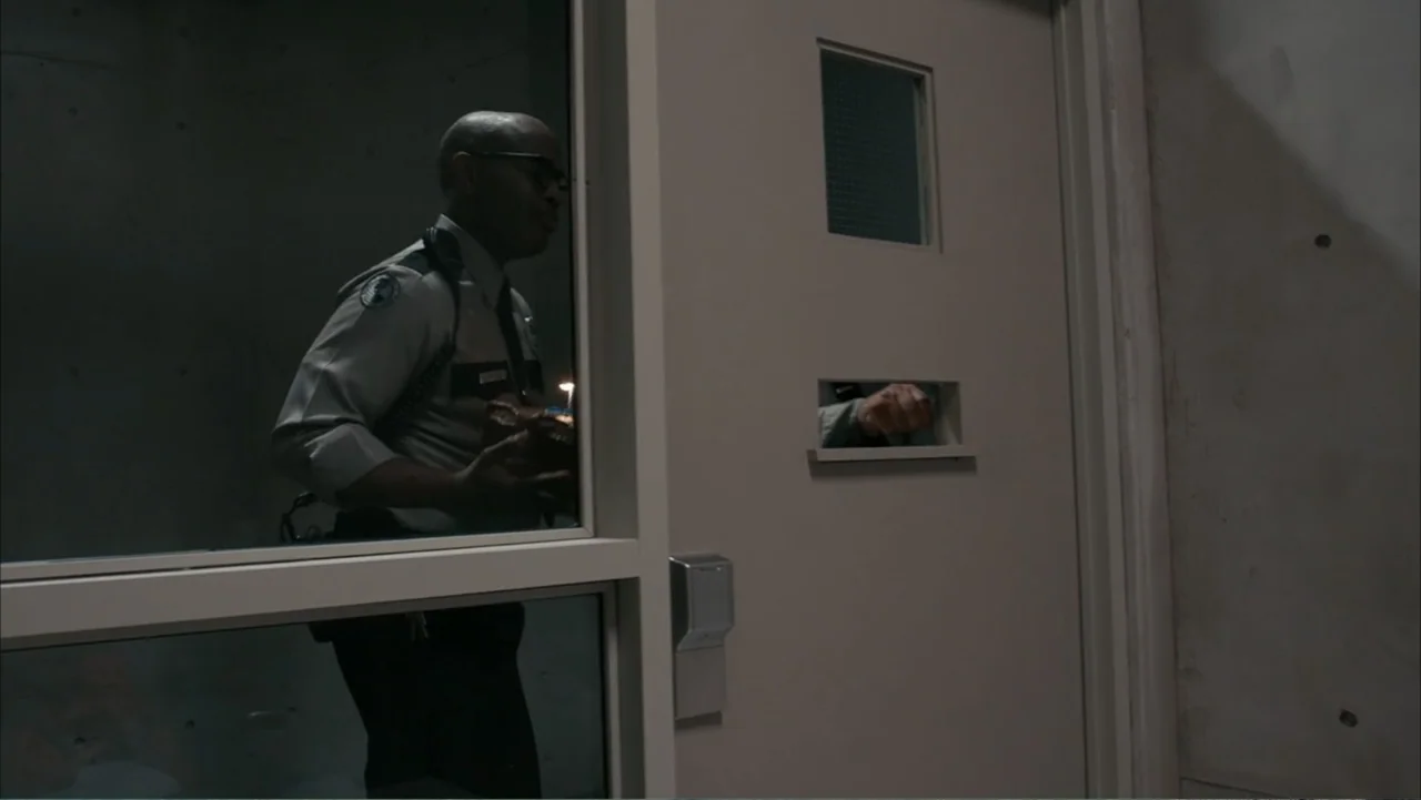Get Smart (2008) movie still: medium — A dimly lit concrete hallway features a heavy door with a small viewing slot. A uniformed security guard…
