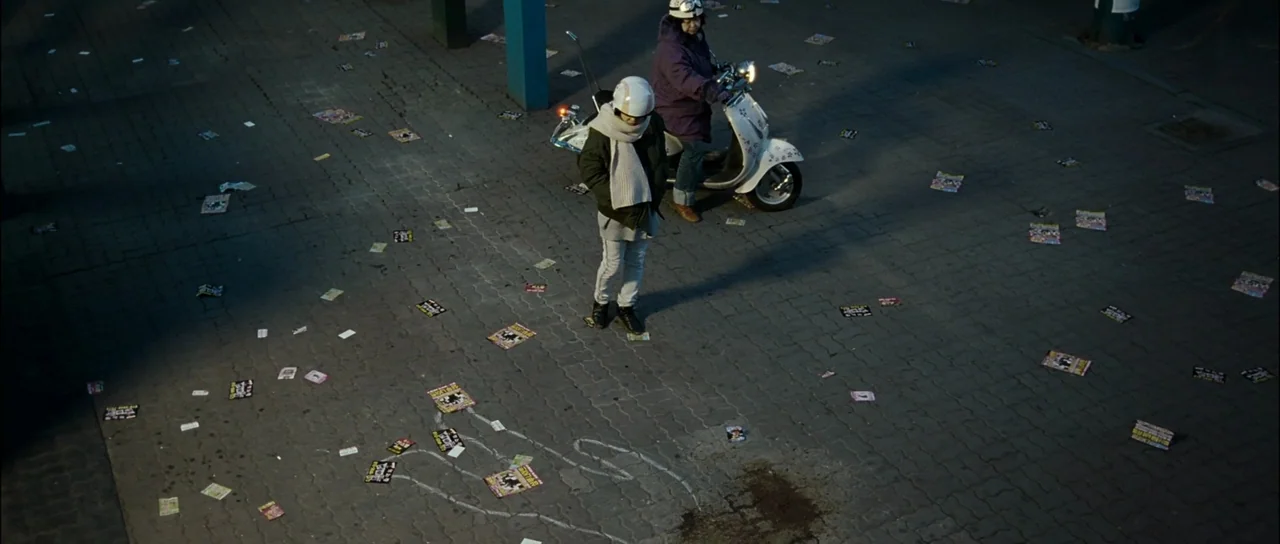 The Housemaid (2010) (2010) movie still: wide — A paved urban square is covered in scattered flyers and white chalk drawings at night. A young…