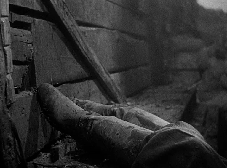 All Quiet on the Western Front (1930) movie still: closeup — A dark muddy trench lined with reinforced wooden beams and earthen walls. Two legs in…