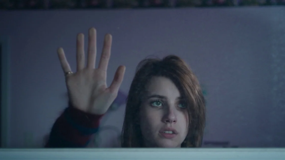 Adult World (2013) movie still: closeup — A dimly lit room with a violet-painted wall is viewed through a mirror. A woman presses her palm flat…