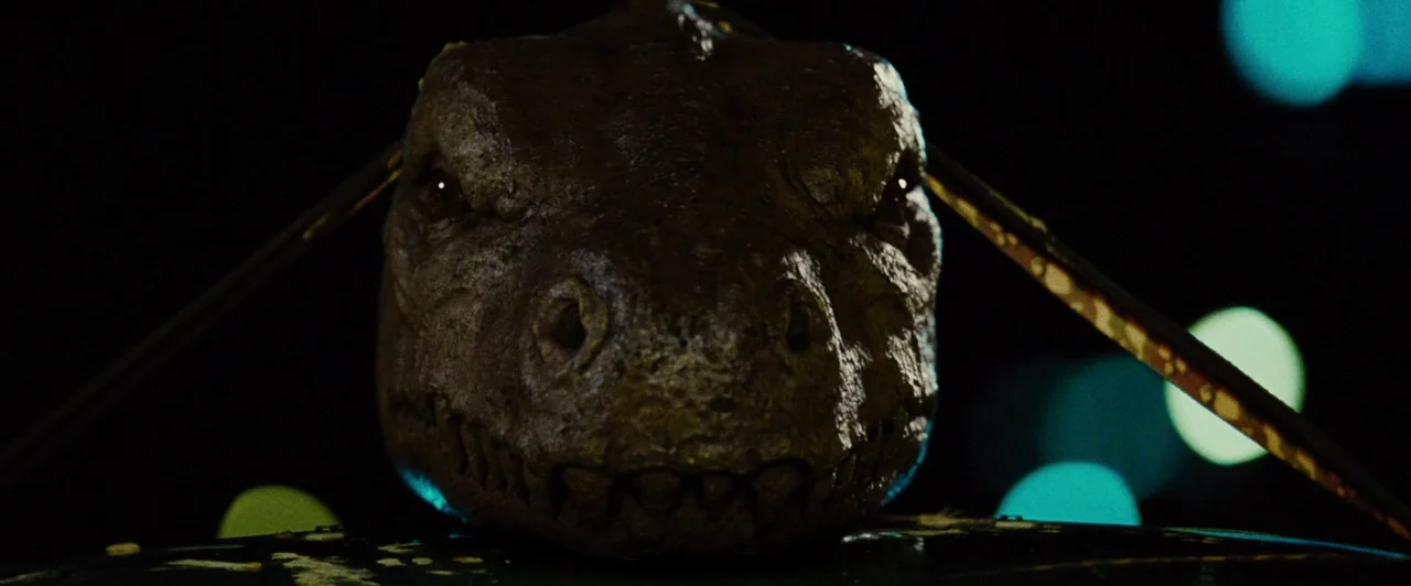 Lost River (2014) movie still: closeup — A dark night setting features a large, detailed reptilian head centered in the frame. The creature…