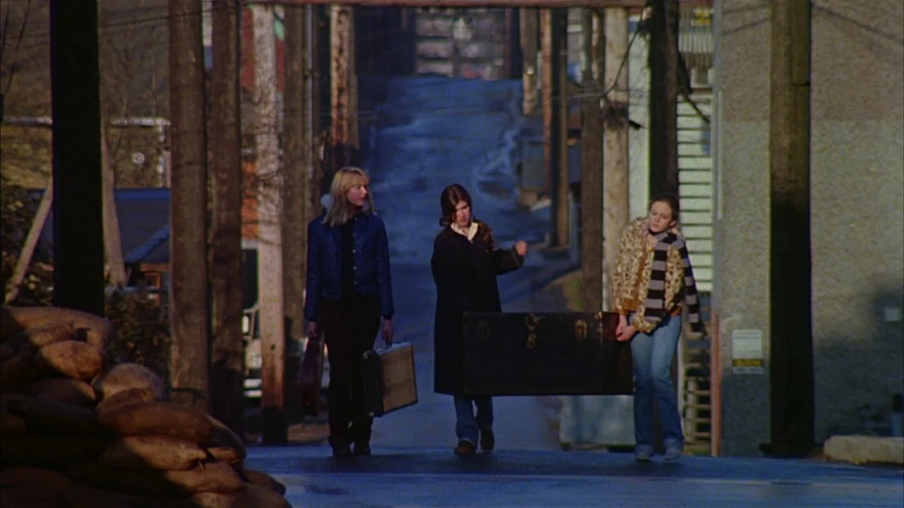 Ladies and Gentlemen, the Fabulous Stains (1985) movie still: fullbody — Three young women walk down a paved road lined with utility poles and…