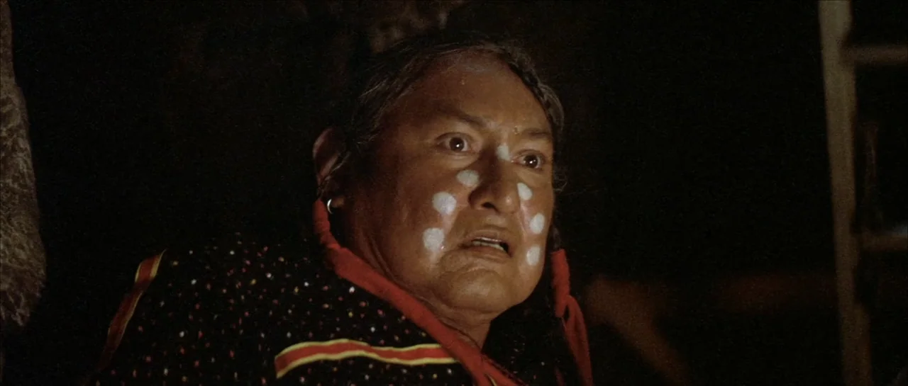 Poltergeist II: The Other Side (1986) movie still: closeup — A dark outdoor environment illuminated by flickering low light at night. An elderly man…