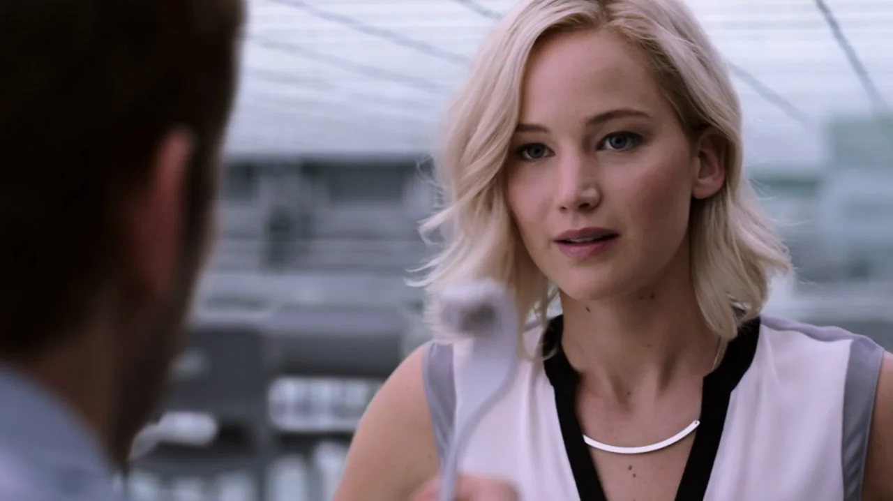 Passengers (2016) movie still: medium — A modern, bright indoor space with white surfaces and diffused light from above. A woman with blonde hair…