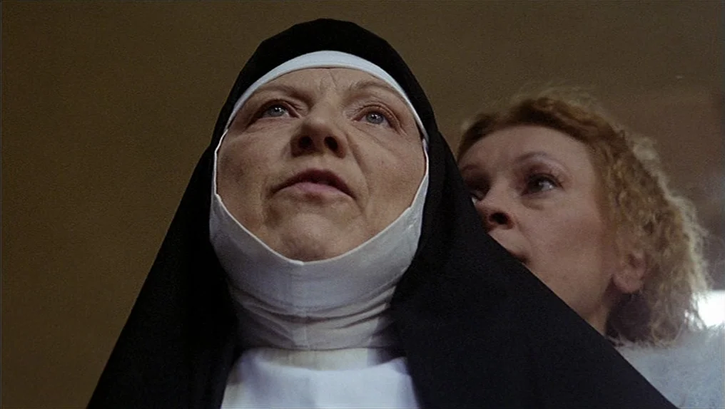 In A Year Of Thirteen Moons (1978) movie still: closeup — A woman dressed as a nun and another person stand close together indoors. The nun is in…