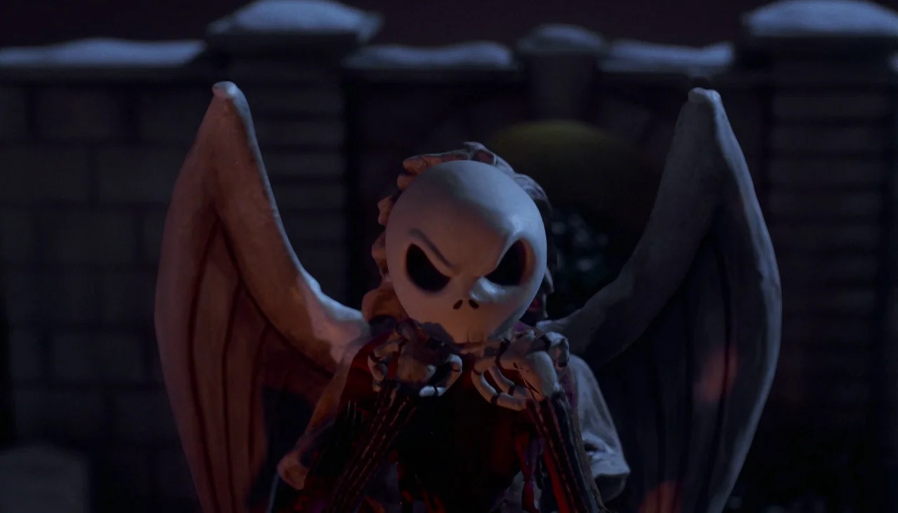 The Nightmare Before Christmas (1993) movie still: closeup — A stone statue with large wings stands against a dark, brick-textured backdrop at…