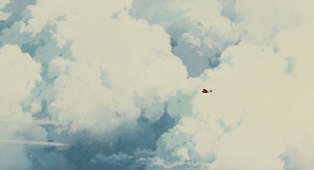 Porco Rosso (1992) movie still: establishing — A vast expanse of white and pale blue cumulus clouds fills the frame. A small red airplane is…