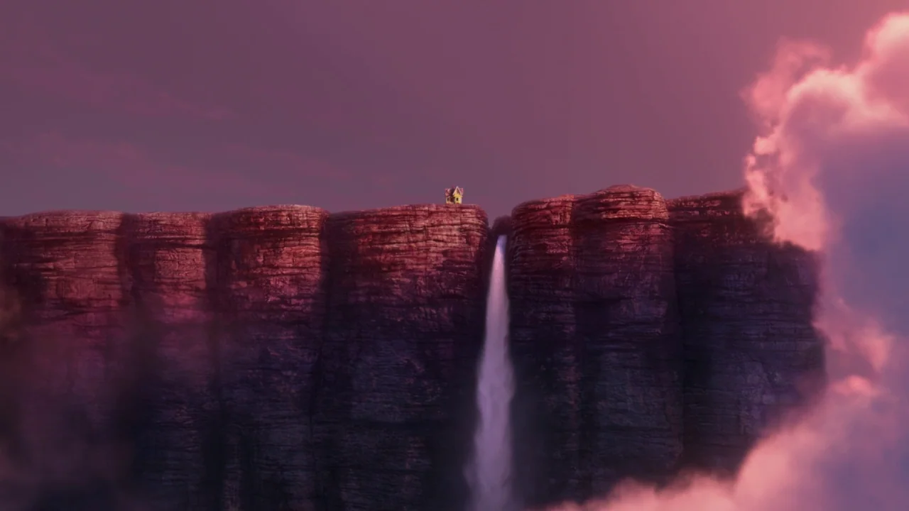 Up (2009) movie still: establishing — A small yellow house stands on the edge of a jagged rock plateau. A narrow waterfall pours from the cliff edge…