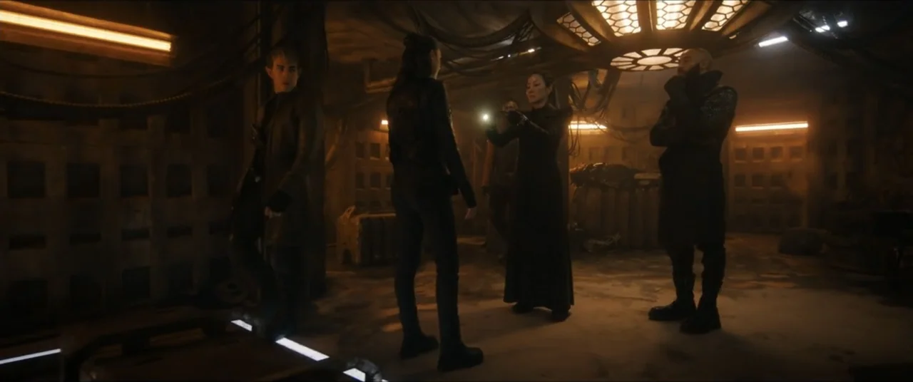 Star Trek: Section 31 (2025) movie still: fullbody — A dark, metallic industrial room features exposed cabling and a large geometric ceiling light…