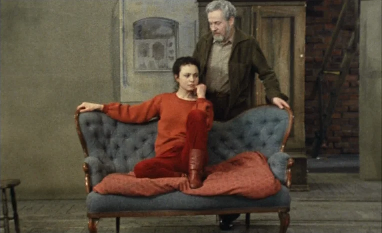 After The Rehearsal (1984) movie still: medium — A spare interior space features a Victorian-style tufted sofa against a painted backdrop wall. A…