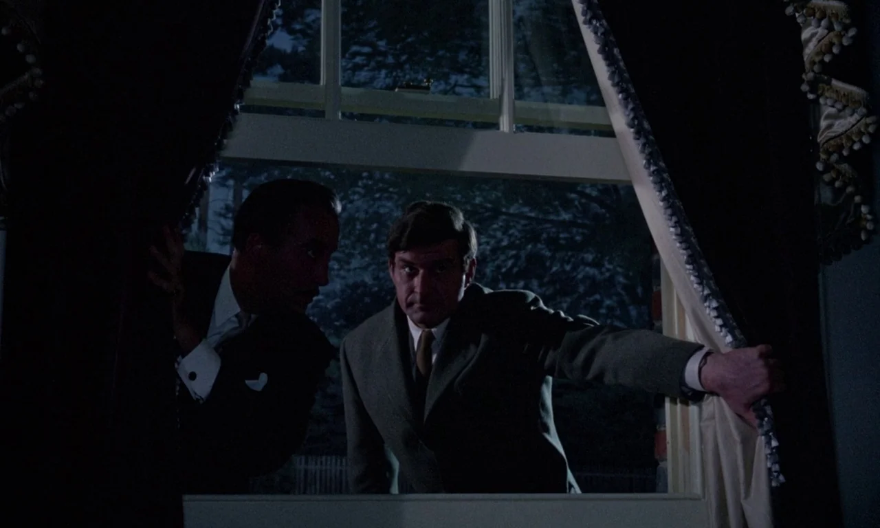 The Devil Rides Out (1968) movie still: medium — Two men stand at a night-lit window inside a room with dark heavy curtains. The men pull the…